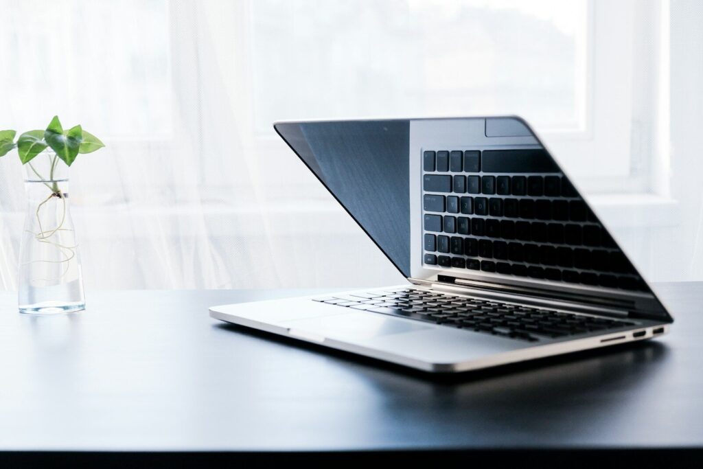 silver macbook pro on white table